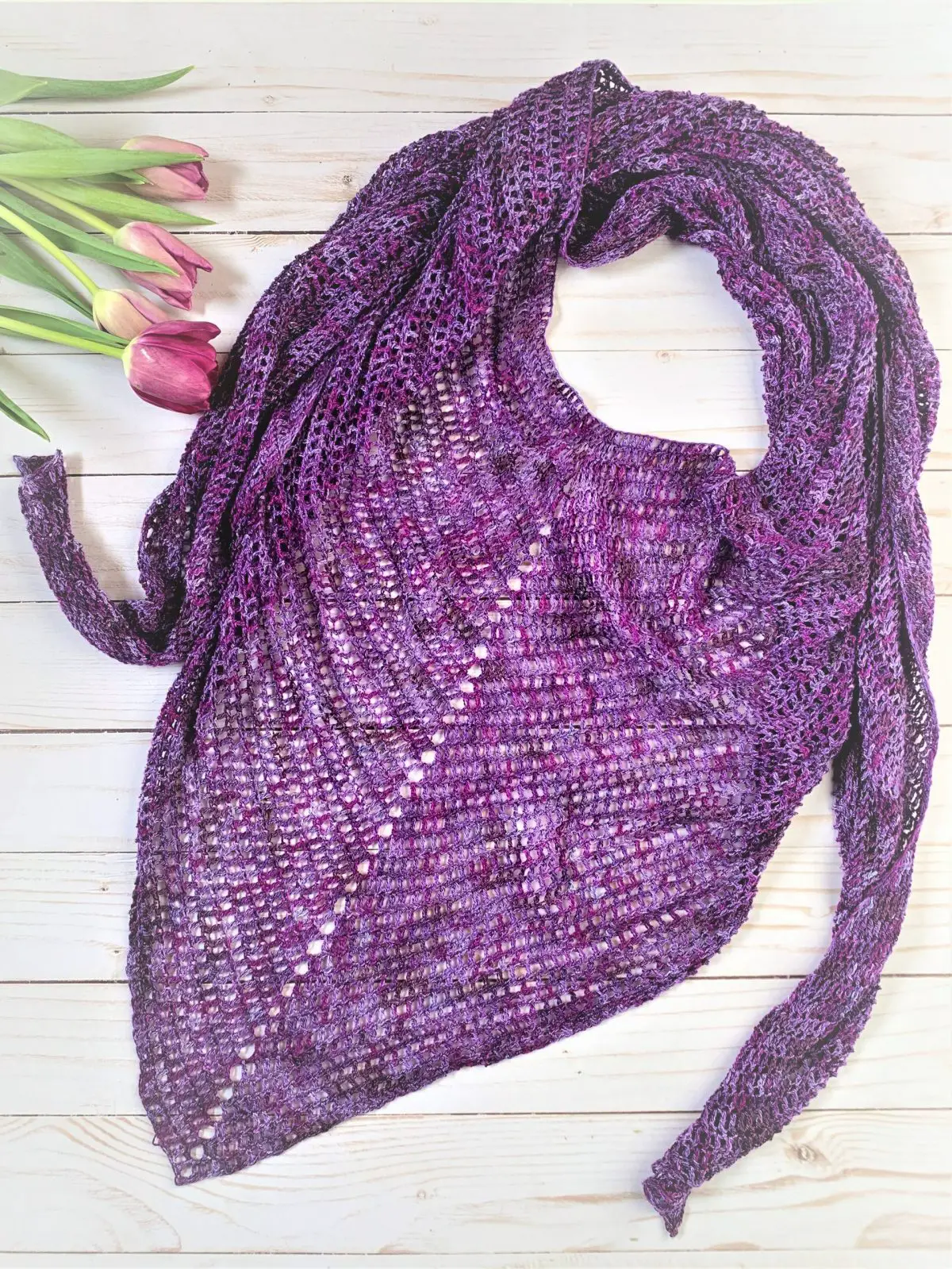 Amethyst Scarf laid flat with fresh purple tulips to the side, over a white wooden planked backing