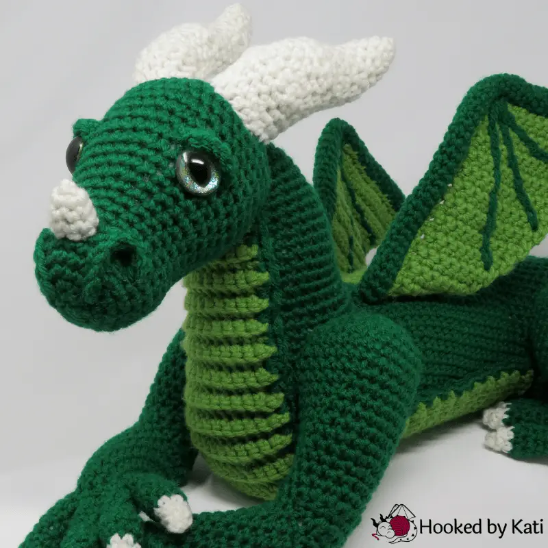 A green amigurumi dragon designed by HookedByKati.