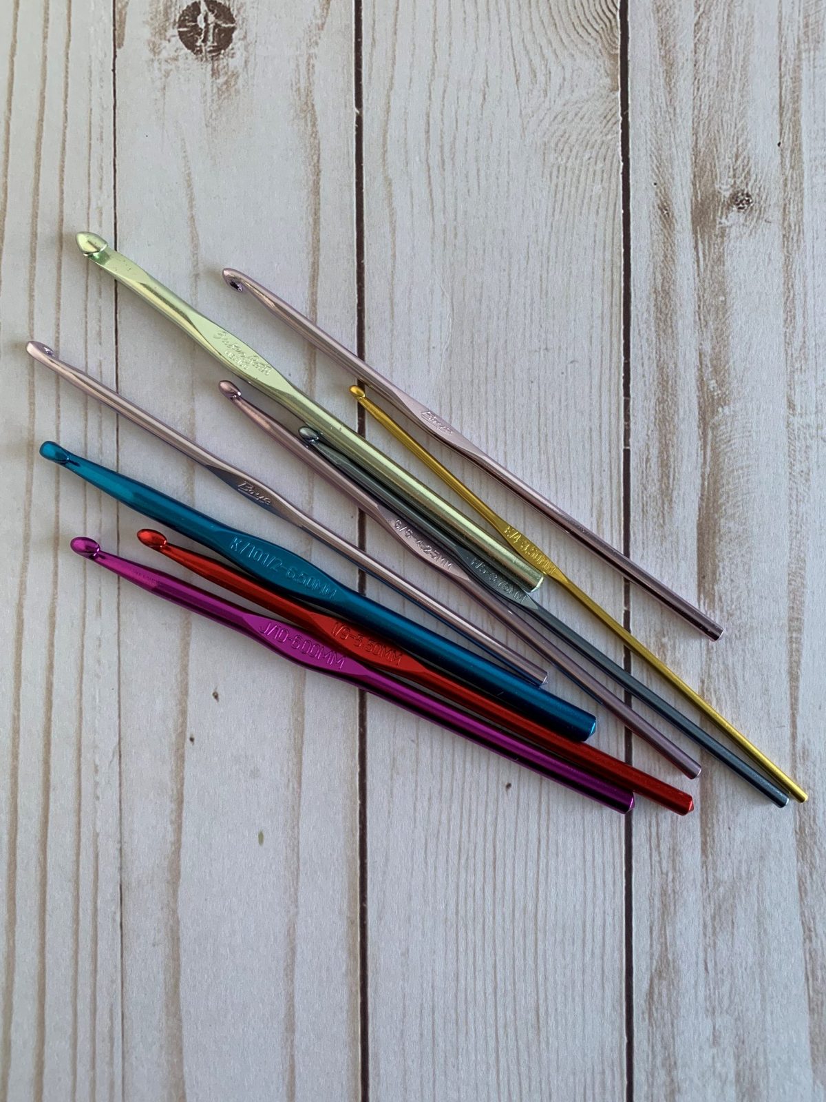 Pile of various crochet hook on a white wooden panelled background